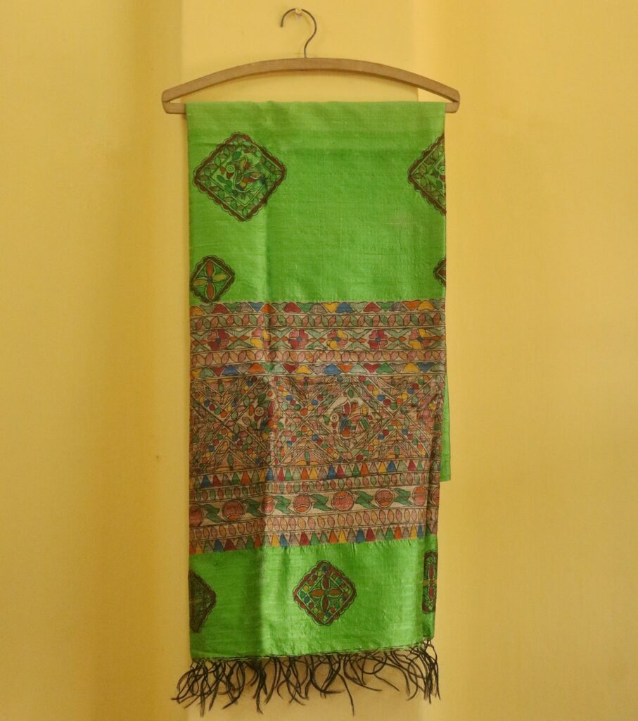 The Emerald Heritage Dupatta brings to life classic Madhubani artistry on a radiant green silk base. Featuring intricate hand-painted motifs framed in geometric borders, this piece is both a celebration of culture and a statement of style. Highlights: ● Lush green silk with handpainted Madhubani art ● Vibrant geometric and floral motifs in natural tones ● Elegant tassels for a graceful finish ● Handpainted to perfection by rural artisans Dimensions: ● Length: 97.5 inches ● Width: 35 inches Material: Blended Silk with Fabric Paint